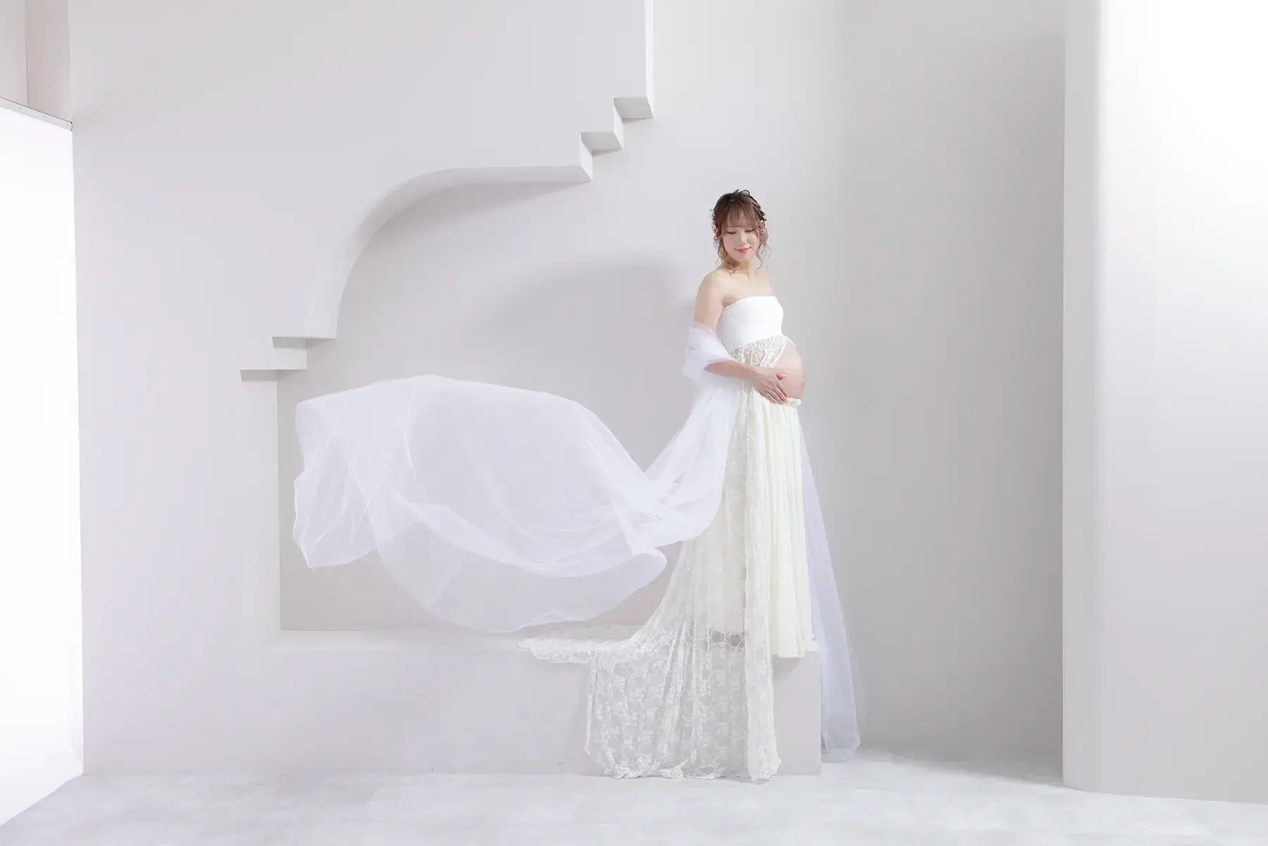 白い衣装を着て花を持ったマタニティの女性
