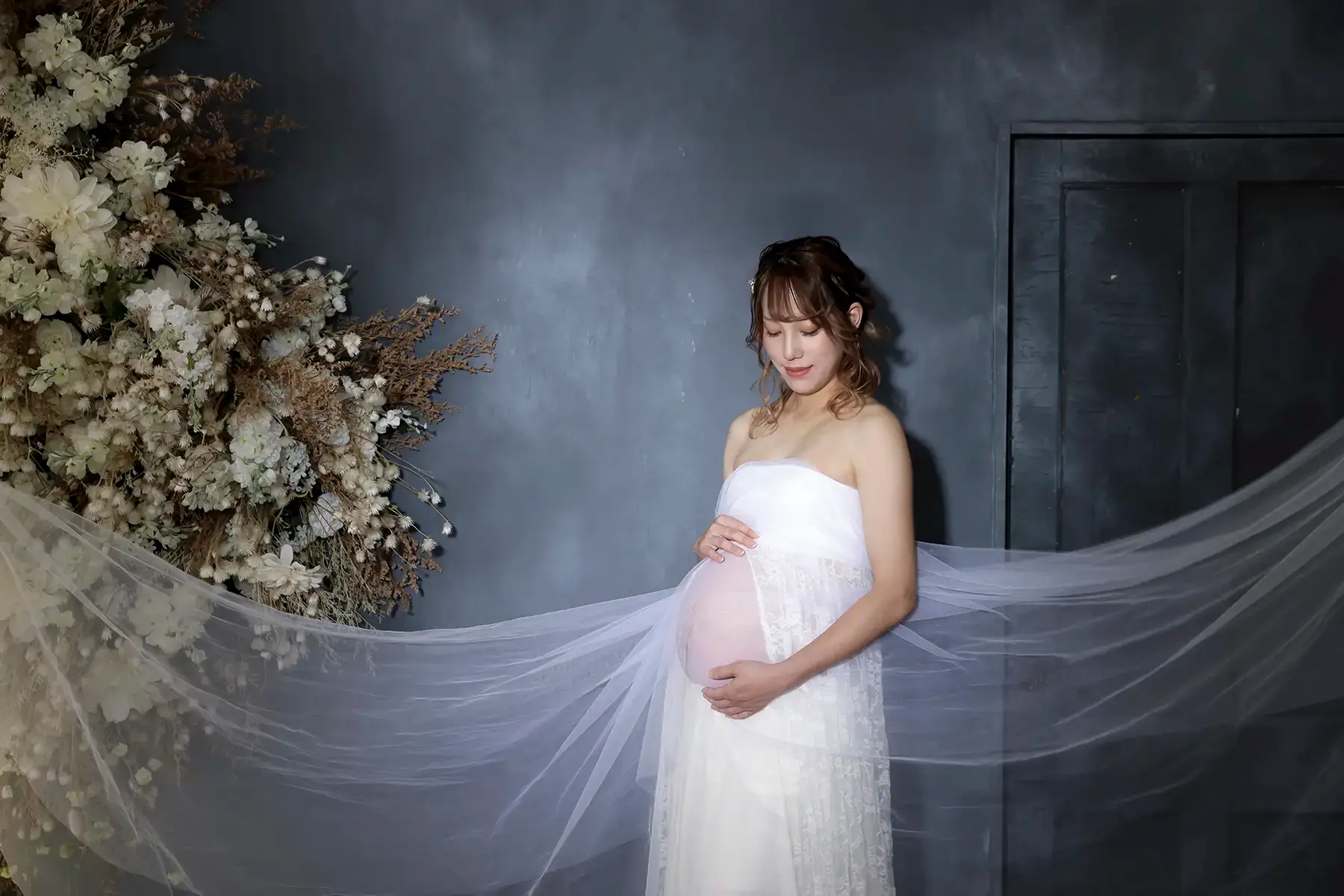 白い衣装を着て花を持ったマタニティの女性