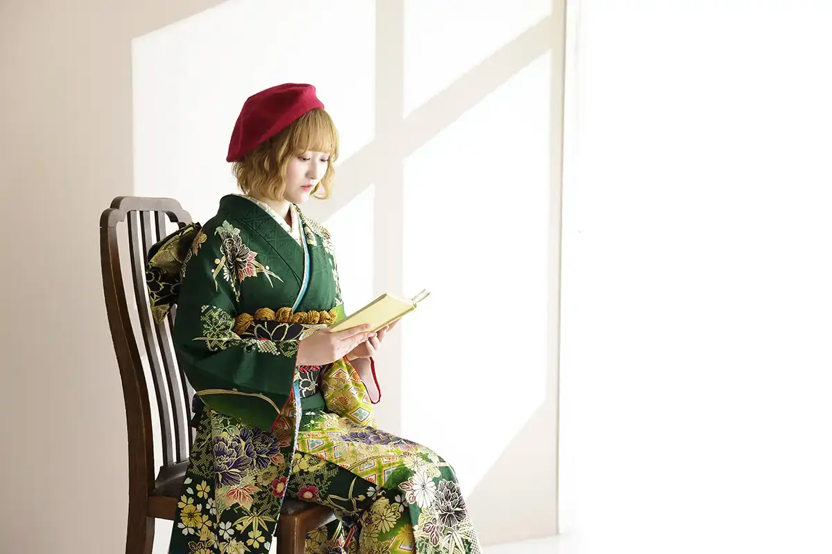 緑の古典柄振袖と赤いベレー帽で本を読む成人女性の記念写真