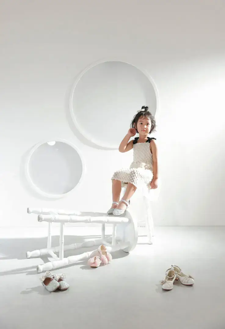 丸窓のある白いスタジオで椅子に座る女の子の記念撮影