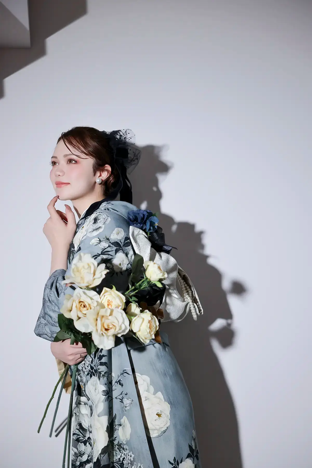 淡いブルーの振袖で白バラの花束を持つ成人女性のポートレート