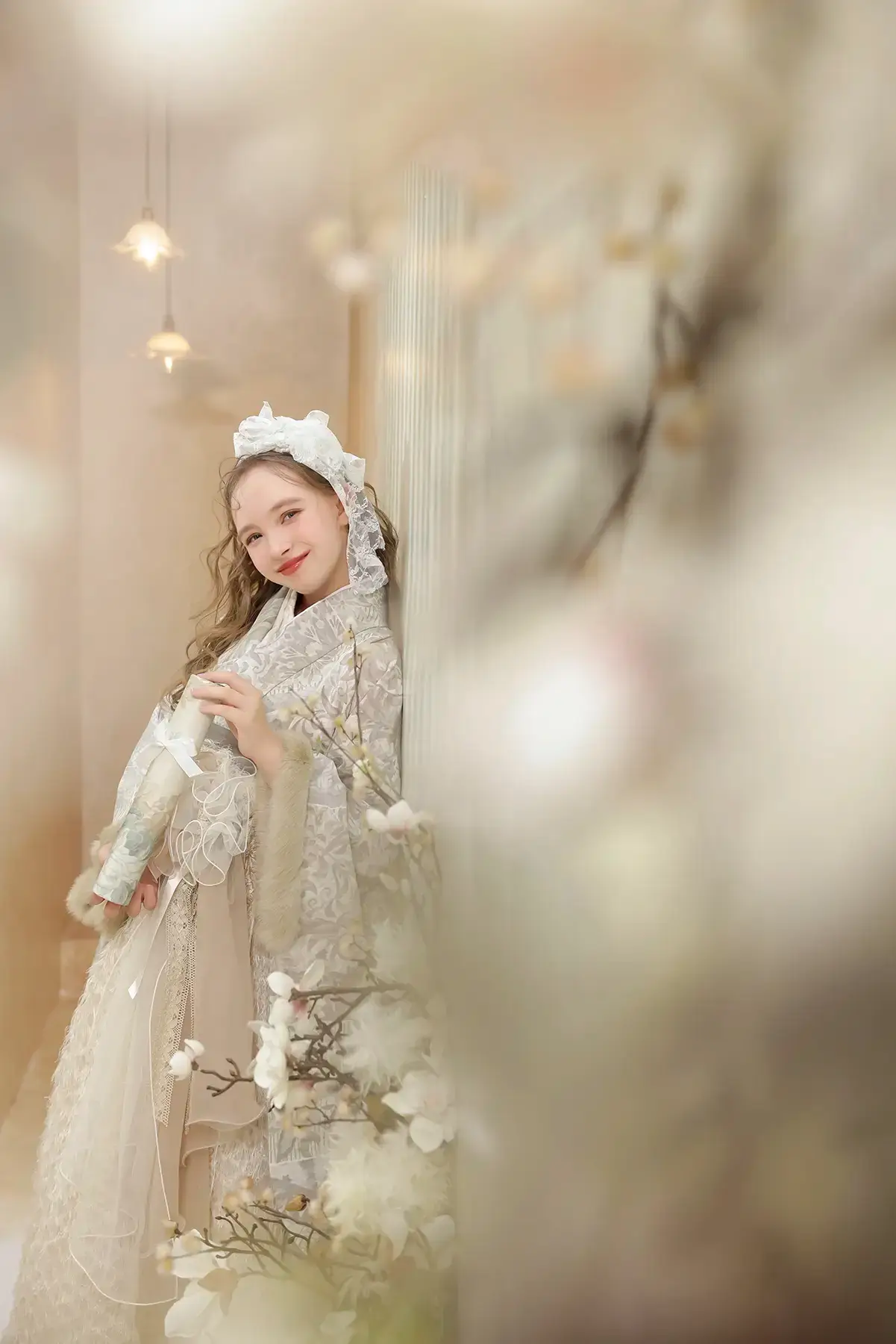 レースのケープと帽子を合わせたスタイルで卒業証書を持つ女の子の記念写真