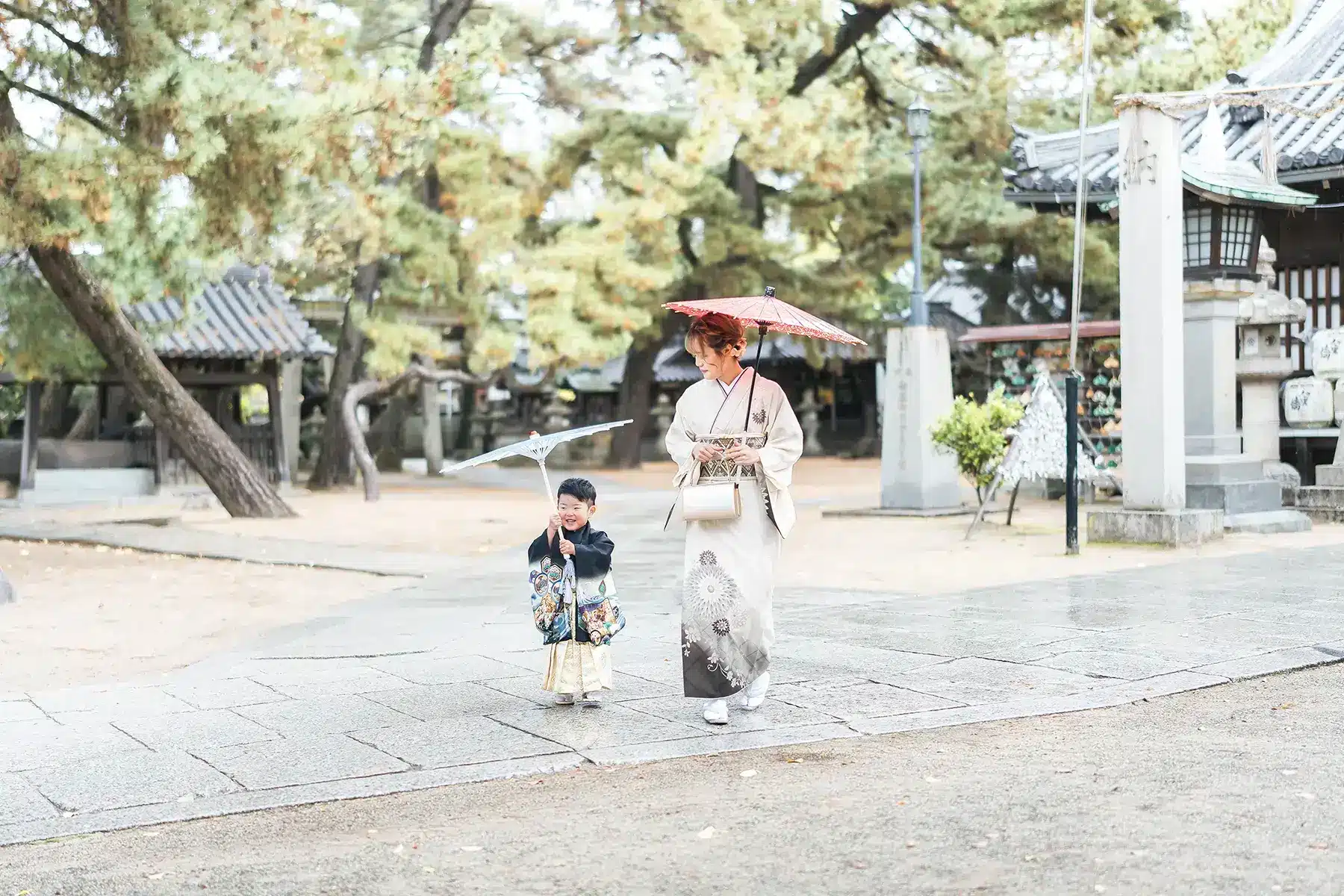 和傘を手に神社を歩く着物姿の親子|お宮参りのロケーション撮影