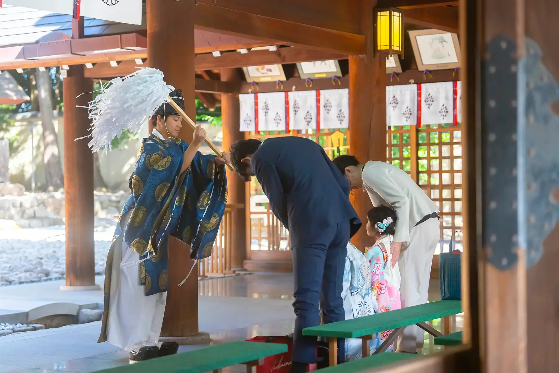神社でのご祈祷中、巫女に祓いを受ける家族と着物姿の女の子