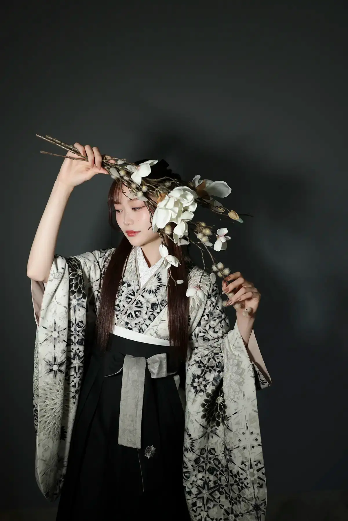 黒背景で白い花とともに撮影された袴姿の女性のアートな卒業記念写真