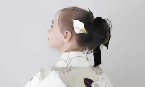 花柄の着物と黒い髪飾りを身につけた後ろ姿のティーン