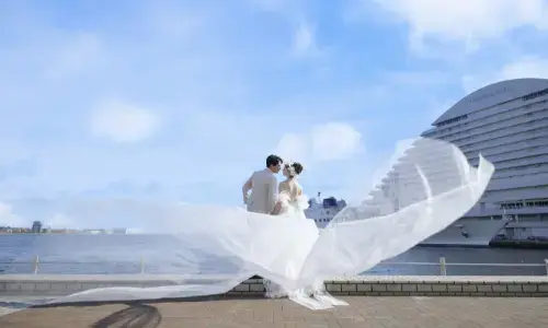 海辺でドレスがなびくドラマチックなウェディングフォト