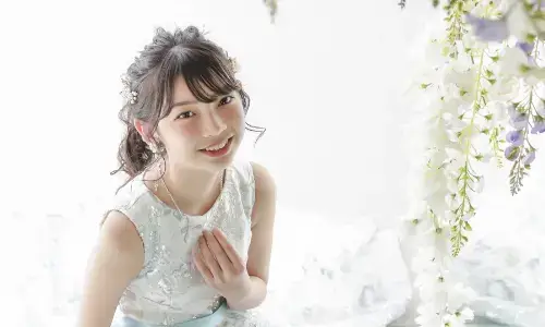 花に囲まれた白いドレス姿で笑顔を見せるティーンのポートレート