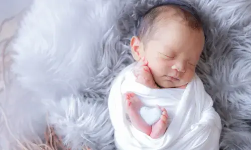 白い毛布に包まれて眠る新生児の愛らしいポートレート