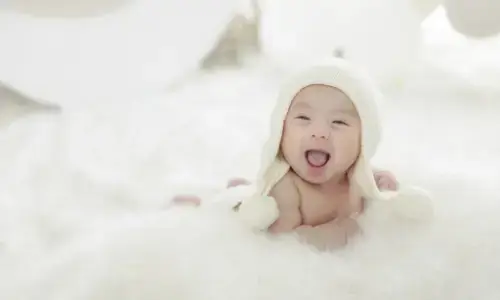 白い帽子をかぶり笑顔を見せる赤ちゃんの記念写真