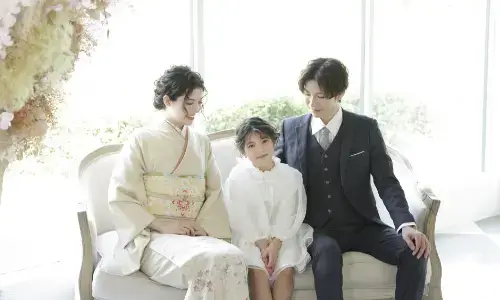 和装の両親と並んでソファに座る女の子の家族写真