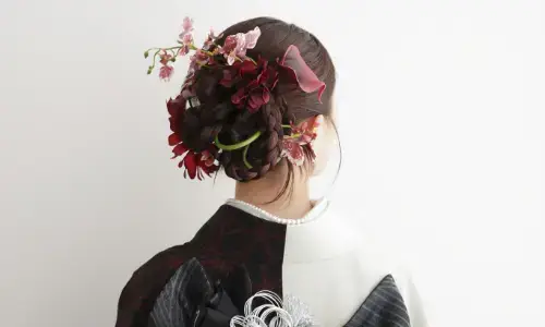 深紅の花飾りが印象的な黒と白の振袖姿の後ろ姿
