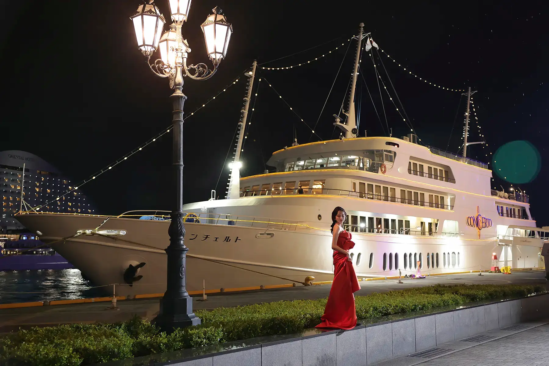 豪華クルーズ船コンチェルト前で赤ドレスを着た花嫁がポーズをとるナイトロケフォト
