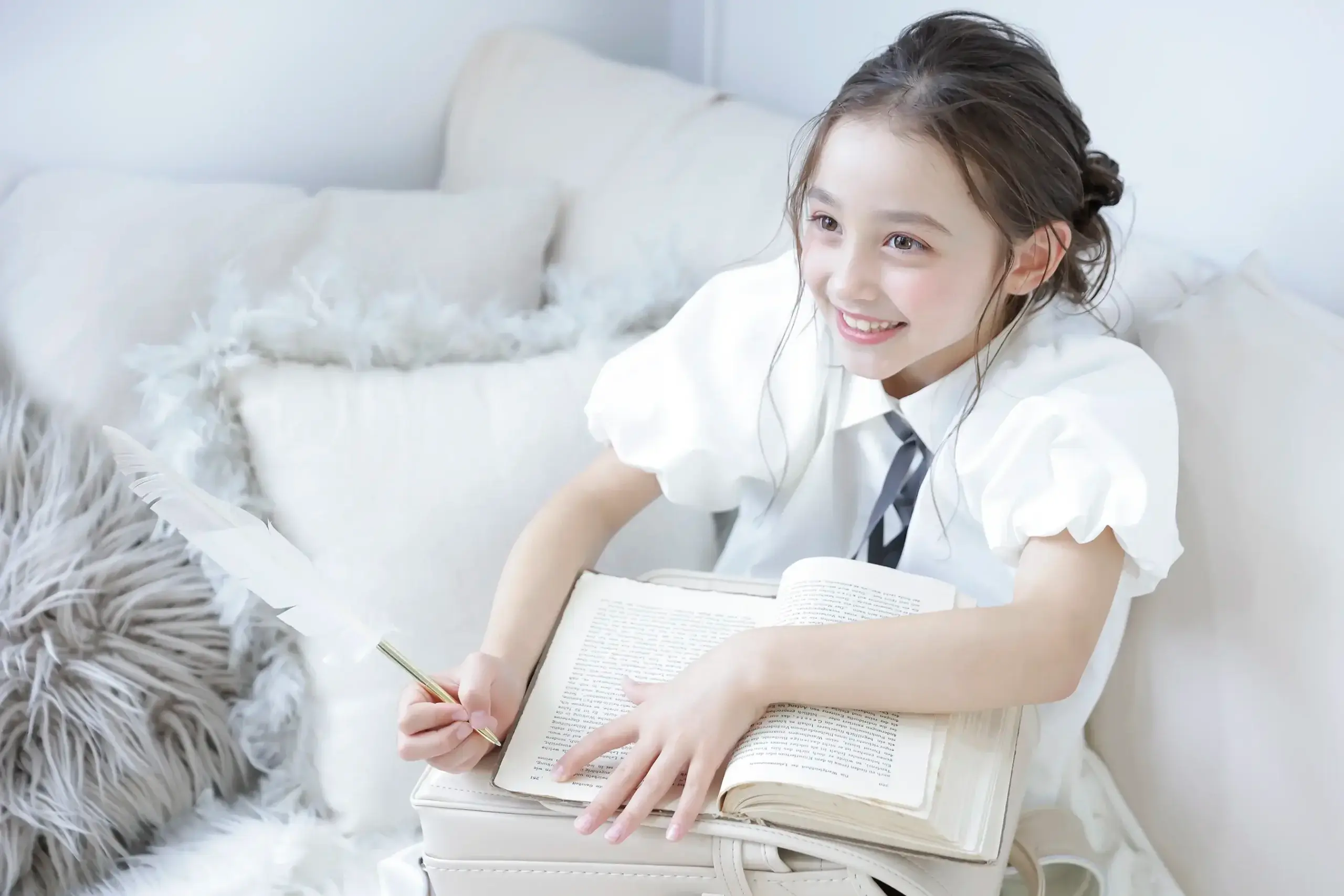 羽ペンで本に書き込むランドセル姿の女の子